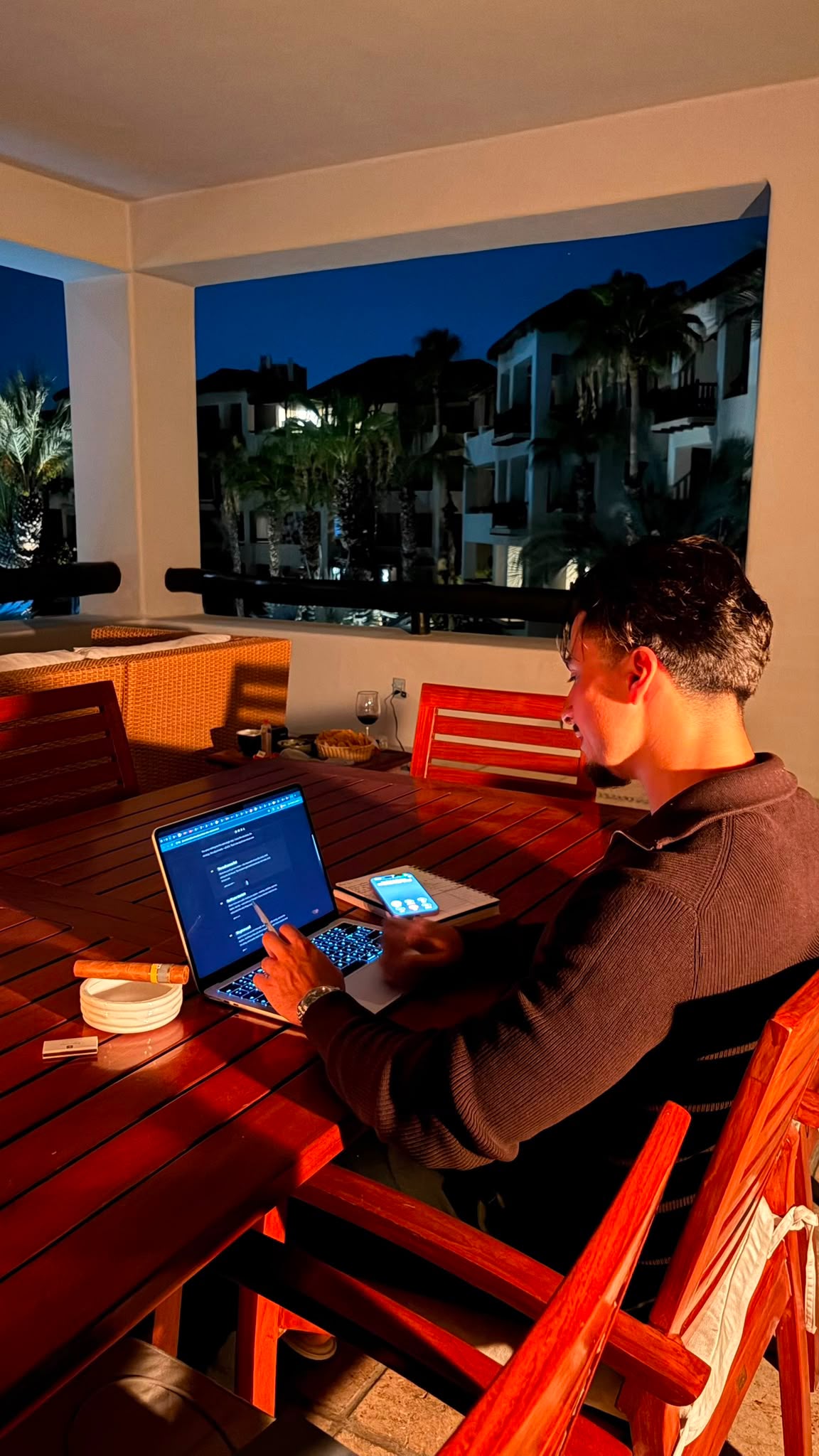 Firas working from a laptop outdoors in the evening
